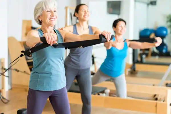Toning Arms After 60: Empowering Womens Fitness Through Effective Weight Training 2 older woman doing weight training Northampton and resistance in the gym to tone upper arms